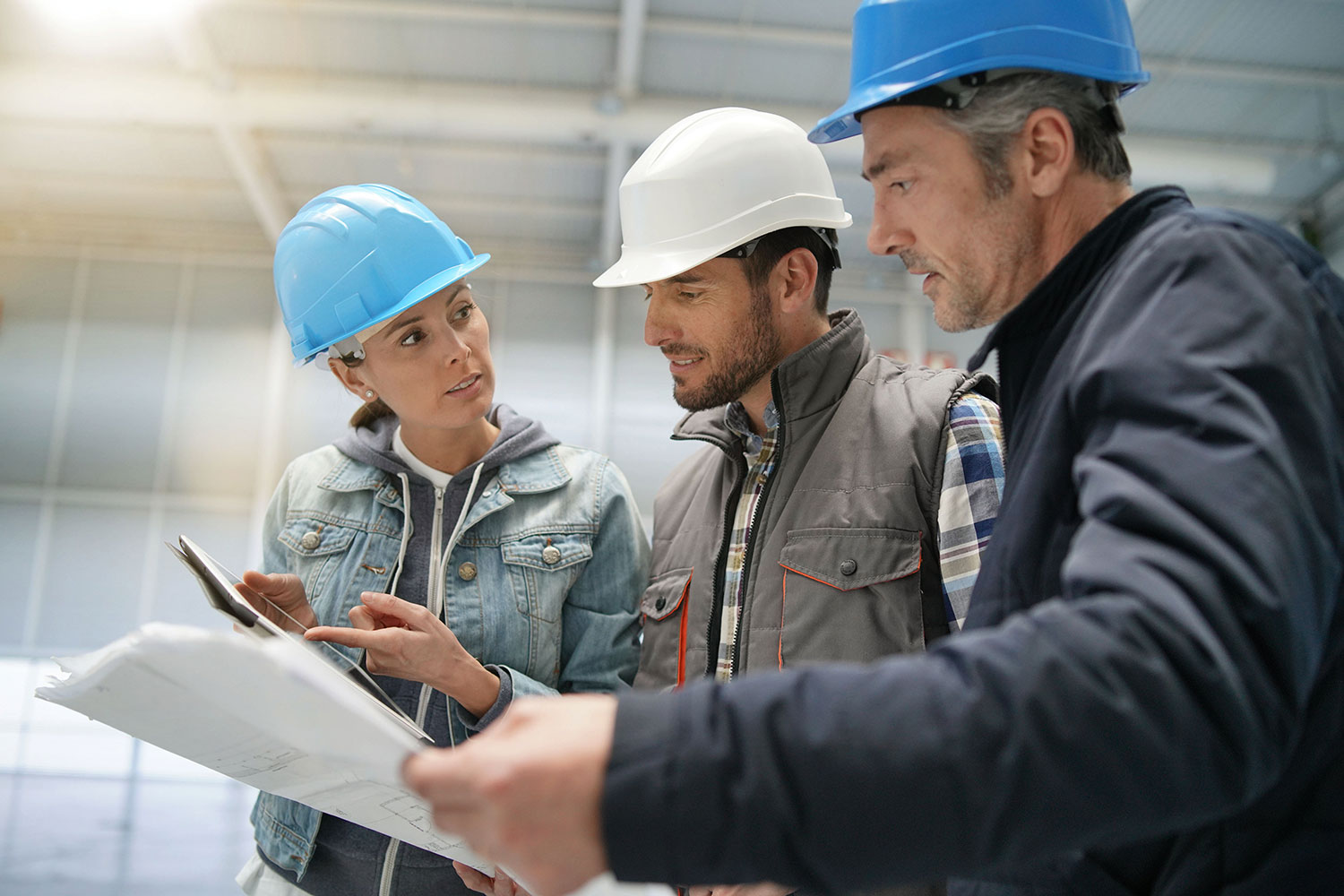 a woman and two men in hard hats looking at TRICOR safety plans